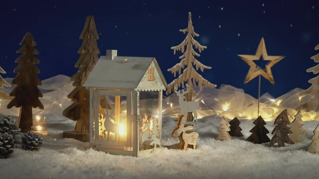 Wooden decoration and lantern arranged in snow, a fantasy forest night landscape footage with falling snowflakes and glowing candles and lights, ideal for Christmas or winter