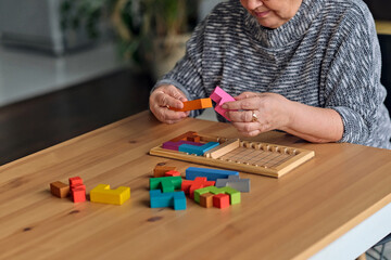 Activity can improve brain function. Elderly woman sitting at table and sorting jigsaw puzzle...