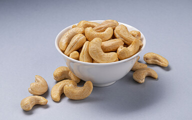Heap of cashew nuts in bowl on white background