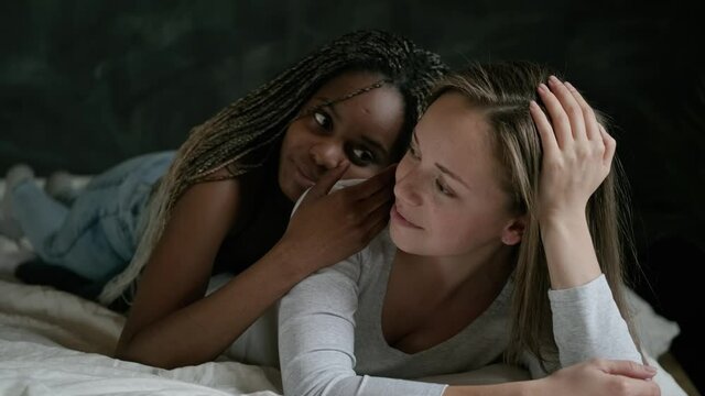 Sensual portrait of a homosexual couple. Lesbians lie in bed and stroke each other with tenderness