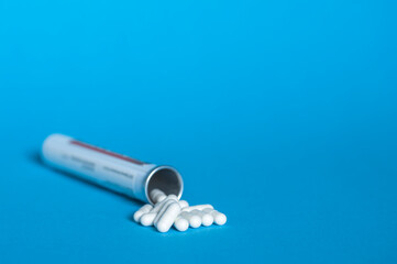 A bottle with a bunch of white capsules of tablets on a blue background.