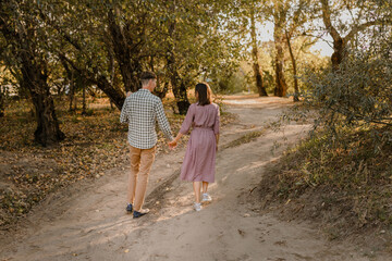 Obraz premium Happy family walking on the road in the park. Father, mother holding baby son on hands and going together. Rear view. Family Ties concept.