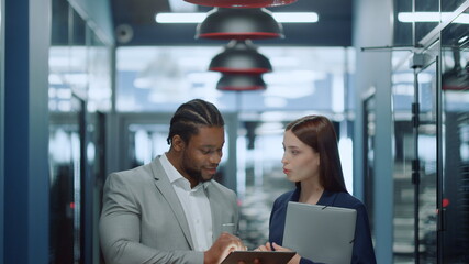 Multiracial couple getting ready for meetup in office. Colleagues using tablet