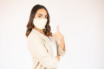 Portrait of a smiling young business woman wearing surgical mask standing with arms crossed isolated over white background