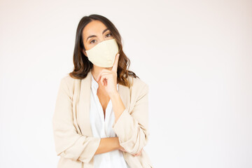 Portrait of a smiling young business woman wearing surgical mask standing with arms crossed isolated over white background