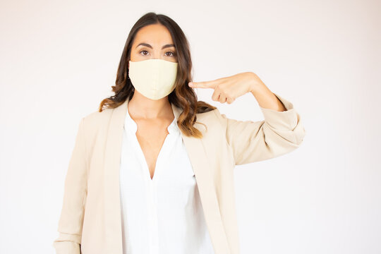 picture of beautiful young woman pointing to mask over white background.