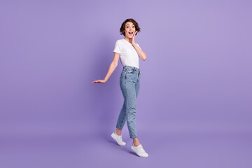 Fototapeta na wymiar Full length body size photo of amazed girl walking touching cheeks wearing casual outfit isolated on bright violet color background