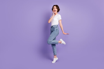 Fototapeta na wymiar Photo portrait full length of adorable girl with open mouth touching face cheek with hand standing on one leg isolated on vivid purple colored background