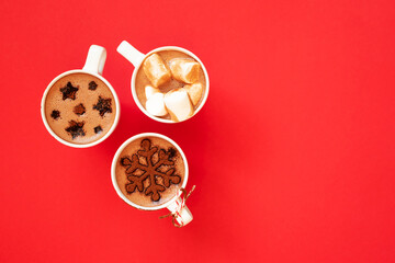Hot chocolate with marshmallows and cocoa powder decor in white cups on red background