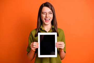 Photo portrait of amazed female student holding tablet showing monitor copyspace winking blinking...