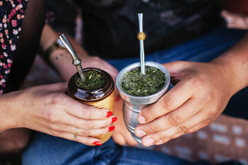 Yerba mate tea in bombilla. Special metal straw. Sout America popular hot drink. Couple drinking...