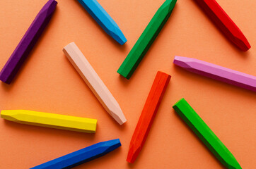 Top view of bright pencils wax on the orange surface