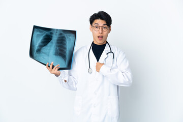 Young Chinese doctor man holding radiography isolated on white background with surprise facial...