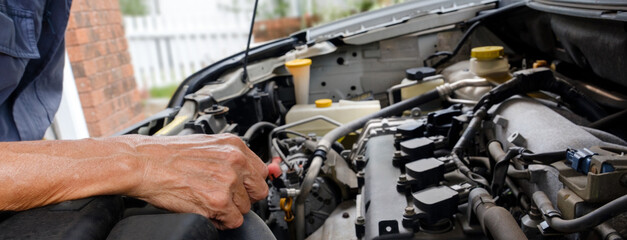 Mechanic checking under the hood or bonnet of a car during a service and repair to find any problems
