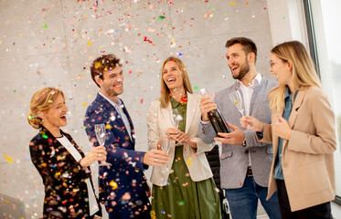 Group of business people celebrating and toasting with confetti falling in the office