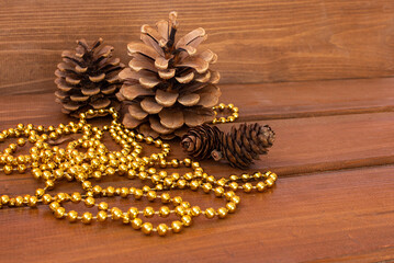 Christmas wooden background, pine cones gold beads. New year background 2021