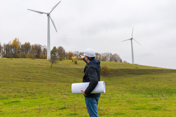 Rear view of engineer male point to the wind turbines windmills, renewable energy and clean power.