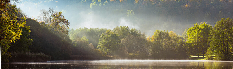Panorama of foggy lake with Autumn foliage and tree reflections in Styria, Thal, Austria
