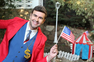 Businessman wearing dollar sign necklace holding US flag
