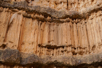 Close up to the light brown stone ancient natural corroded wall up in the mountain, with the abstract curve pattern