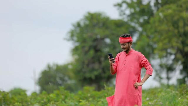 Young Indian farmer using smartphone at green eggplant field