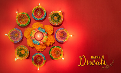 Happy Diwali - Clay Diya lamps lit during Dipavali, Hindu festival of lights celebration. Colorful traditional oil lamp diya on pink background