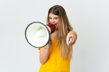 Young blonde woman isolated on white background shouting through a megaphone to announce something...