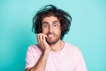 Portrait of crazy stressed uncombed hairdo guy bite nails wear spectacles pastel pink t-shirt isolated on teal color background