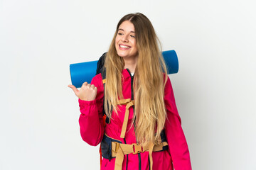 Young mountaineer woman with a big backpack over isolated background pointing to the side to present a product