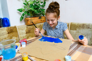 a girl drawing blue gouache cardboard, artistic creation at home, makes creative artwork