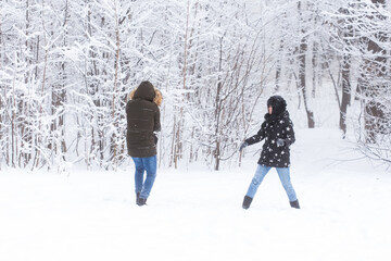 Lifestyle, season and leisure concept - Funny couple playing snowball in winter park