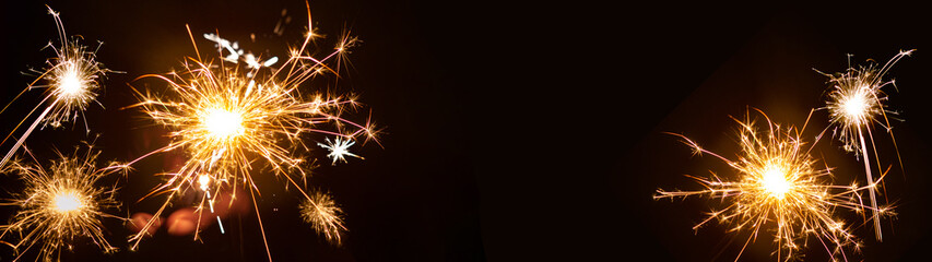 Fototapeta premium Silvester / New year background banner panorama - People hold sparkling sparkler in her hand at dark night