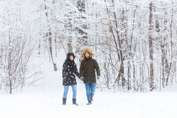 Fototapeta na wymiar Young couple in love walks in the snowy forest. Active winter holidays.