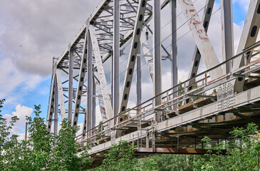 Iron railway bridge over the river against a cloudy sky