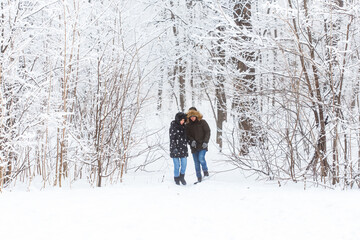 Fototapeta na wymiar Young couple in love walks in the snowy forest. Active winter holidays.