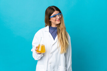 Young blonde scientific woman isolated on blue background and looking up