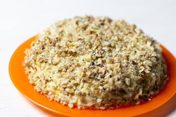 Salad with walnut, mayo, chicken, cheese, onion, potato on orange plate on white background