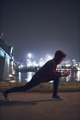 Athletic sporty man training in hoodie sweatshirt in urban / city environment.