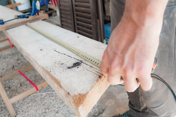 Male carpenter working with wood material in a garage.