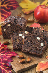 Autumn or christmas fruit cake with apples on a wooden board, decorated with coloured leaves, vertical stock photo