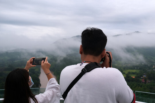 person taking pictures against foggy mountain background
