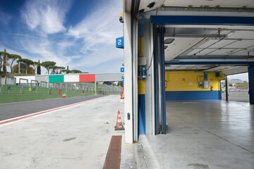 Pit lane motor sport circuit empty no people and workshop box entry, italian flag colours in background