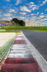 Sunrise on empty asphalt track motorsport circuit calm before storm concept curb close up surface level