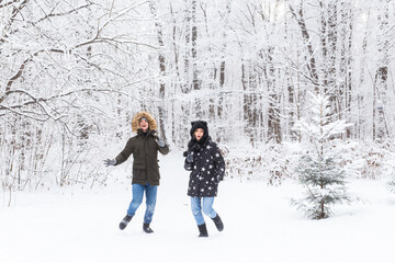 Fototapeta na wymiar Fun, season and leisure concept - love couple plays winter wood on snow