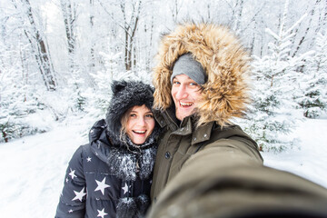 Obraz premium Season and relationship concept - Funny couple taking selfie in the winter time