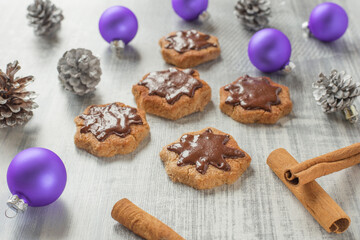 Christmas composition with freshly baked cinnamon cookies, purple,  Christmas balls, pine cones on a light background. New Year's composition..