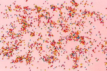 Festive mood, colored pastry sprinkles on a pink background