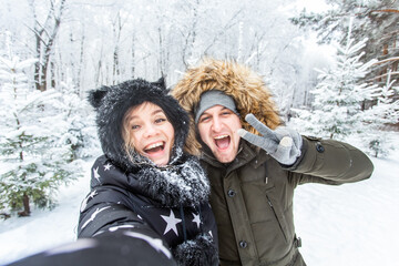 Season, love, technology and leisure concept - happy couple taking selfie by smartphone over winter background