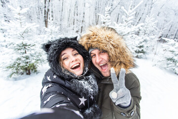 Fototapeta na wymiar Season and relationship concept - Funny couple taking selfie in the winter time