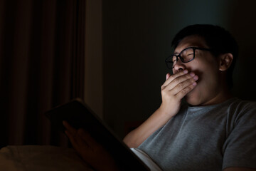An Asian man between the ages of 35 and 40 plays a laptop in his bed. Concept of technology, poor...